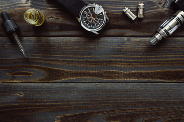 Vaping set and watch with copy space on the wooden background. Hipster or bussinesman style.