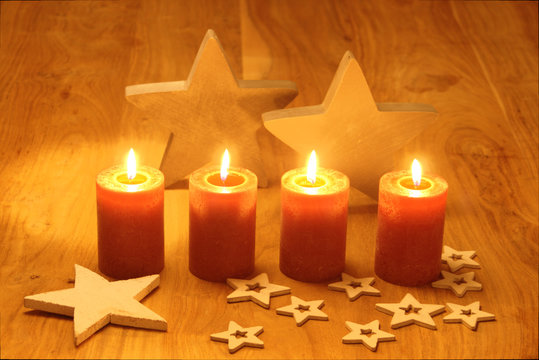 Weihnachtsmotiv mit brennenden Kerzen und Weihnachtssternen