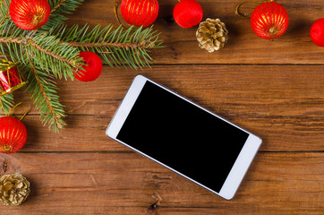 Smartphone and Christmas decoration on a wooden table.