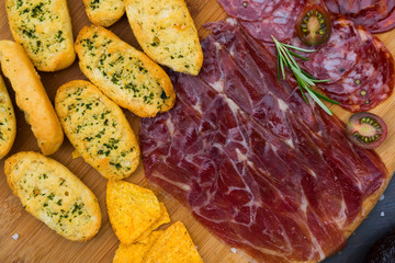 Plate with spanish jamon ham and chorizo tapas, picnic table top view