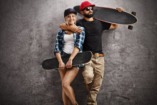 Skaters posing with longboard and skateboard and leaning on rust