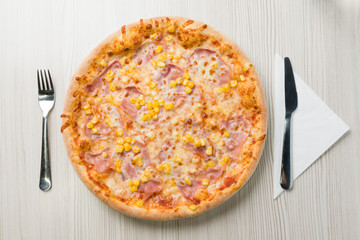 Pizza with ham and corn on the table