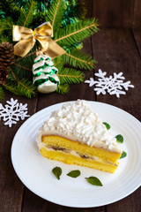 A large piece of delicate sponge cake decorating air cream. Festive dessert on a wooden background. To celebrate Christmas, New Year's Eve.