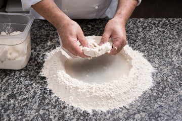 Mani di uomo che lavorano la farina bianca per fare  l’impasto del pane