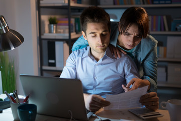 Young couple checking bills at night