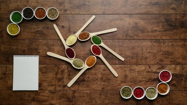 Spices in spoons and bowls moving on wooden background. Stop motion animation.