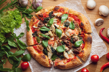 Fresh pizza with ingredients on wooden table