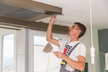 Construction worker wearing worker overall with wall plastering tools renovating apartment house....