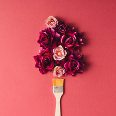 Purple flowers and paint brush on pink background.