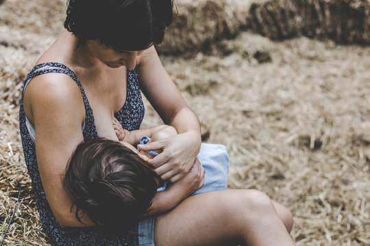 Ni&ntilde;a mamando de el pecho de su madre en un parque