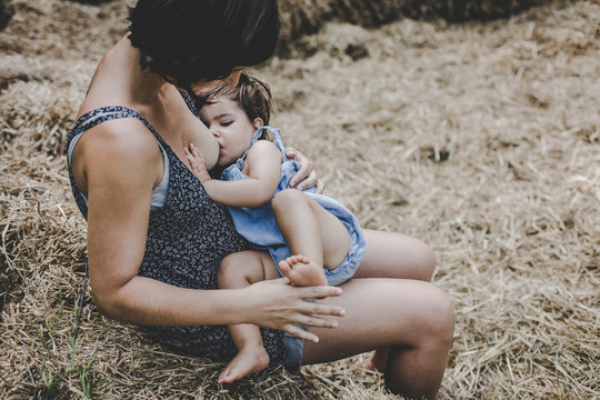 Ni&ntilde;a mamando de el pecho de su madre en un parque