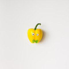 Yellow pepper with eyes and bowtie on white background.