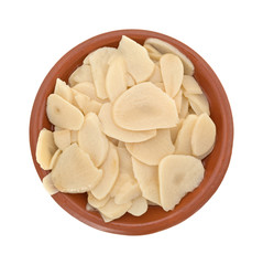Sliced garlic in a bowl on a white background top view.