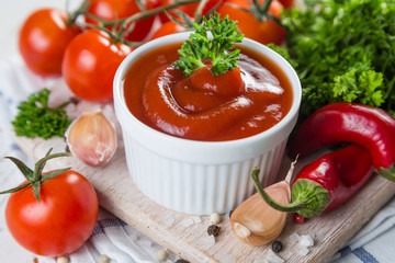 Ketchup and ingredients on wood background