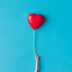 Doll hand with heart shaped baloon. Minimal concept. Flat lay.
