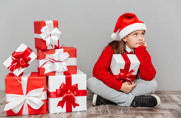 Bored little girl in santa claus hat with gift box