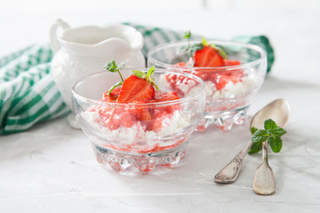 summer breakfast - cottage cheese with strawberry in a glass bowl on a table, selective focus