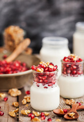 Fresh yogurt with pomegranate seeds and walnut in a glass jars