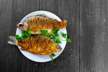 fried fish on a white plate on a wooden background