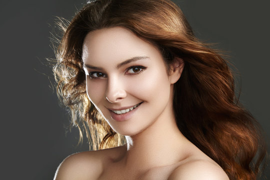Beautiful young woman model with flying brown color hair. Beauty portrait with clean skin, glow glamour fashion makeup. Make up, curly hairstyle. Hair-care, make-up. Horizontal beauty portrait