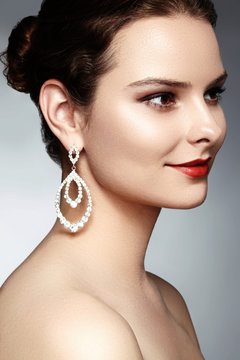 Beautiful happy woman in luxury fashion earrings. Diamond shiny jewelry with brilliants. Sexy retro style portrait. Model with glamour accessories jewelery and bright red lips makeup