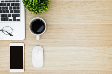 Wood desk table with laptop, coffee, smartphone and supplies. Top view with copy space, flat lay.