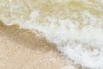 Fototapeta na wymiar Ocean wave splashing on a brown sandy beach
