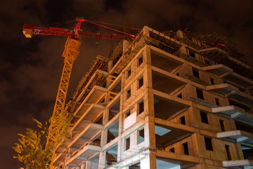unfinished building and hoisting crane at night time