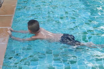 Boy swimming in the swimming pool happy.