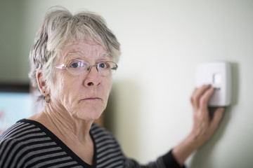 Senior woman adjusting her thermostat