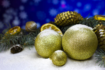 Collection of golden Christmas baubles and dry oranges fruit, tree fir brunch, gold pin cone, walnut in snow