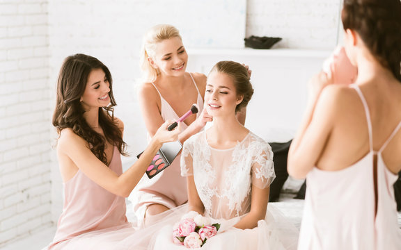 Cheerful bridesmaids preparing the young bride to the wedding ceremony