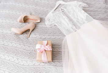 White wedding dress and shoes lying on the bed