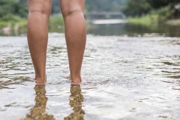 Woman legs while standing the river.
