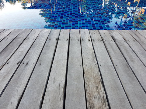 Close focus of edge of wood floor near swimming pool.