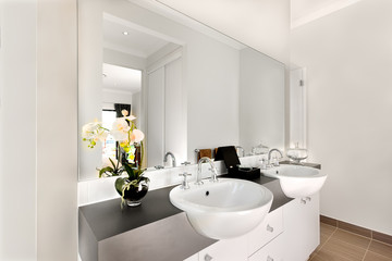Close view of a modern bathroom included a big mirror and white
