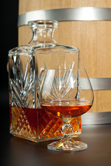 Glass of brandy and a carafe on  background  oak barrels