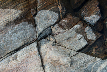 close up of large cracked rock on lake shore