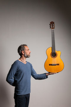 Man with classical guitar. Musician balances his guitar in the palm of his hand.