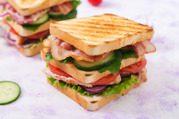 Club sandwich with chicken breast, bacon, tomato, cucumber and herbs