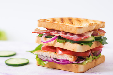 Club sandwich with chicken breast, bacon, tomato, cucumber and herbs