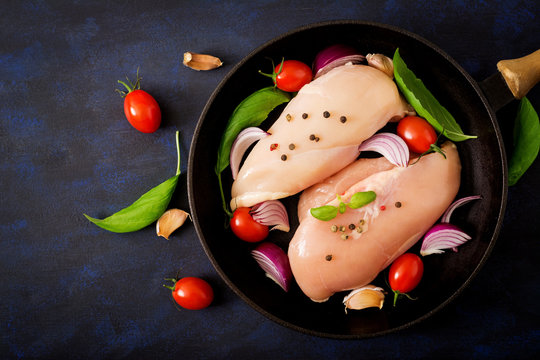 Raw chicken fillet prepared for baking in a pan on a dark background. Top view