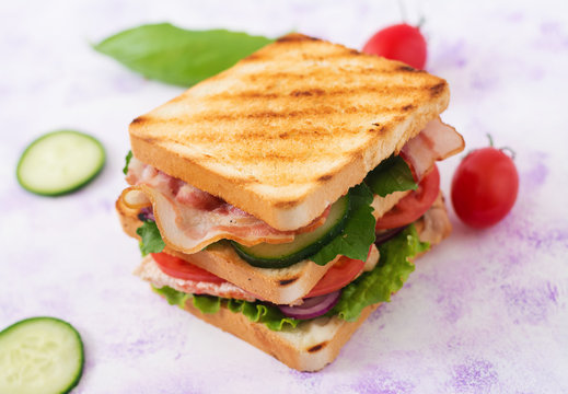 Club sandwich with chicken breast, bacon, tomato, cucumber and herbs