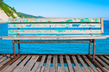 Naklejka na ściany i meble Old rusty bench at pier in the sea