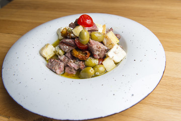 Sliced beef pot with cheese, olives, potato, tomato in sauce