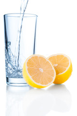 Glass of water and lemon on white background