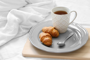 Cup of tea and croissants wooden tray. Breakfast in bed