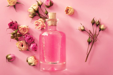 Fototapeta na wymiar Bottle of aroma oil with roses, top view