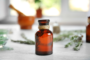 Bottle of rosemary essential oil on wooden table