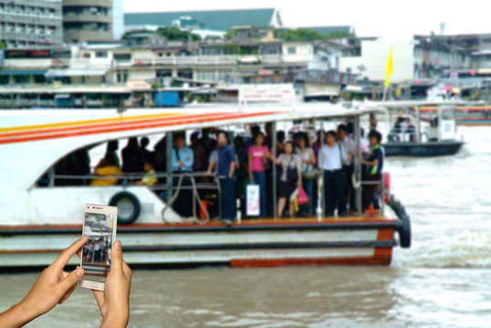 Hand of photographer with smart phone shooting image on blurred passenger on boat background.